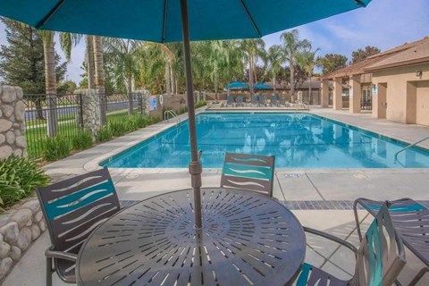 a swimming pool with a table with chairs and an umbrella