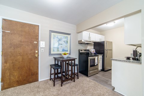 a kitchen and living room with a small table and a refrigerator