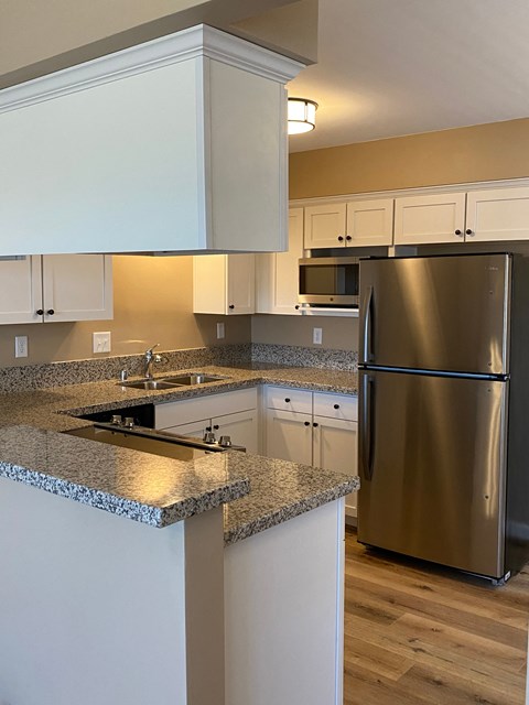 a kitchen with granite counter tops and a stainless steel refrigerator