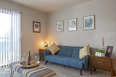 a living room with a couch and a table with a bottle of wine