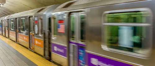 A New York City subway train arriving at a station, with its colorful exterior and platform visible.