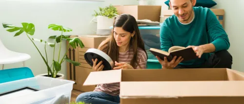 Two roommates unpacking boxes in their new home.