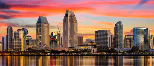 San Diego skyline at sunset with colorful sky and waterfront reflections.