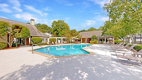 a swimming pool with lounge chairs and trees in the background