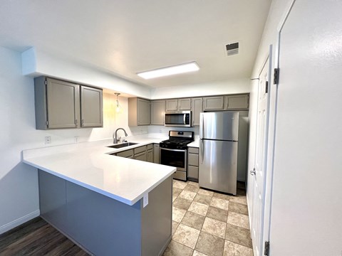 a kitchen with white countertops and stainless steel appliances