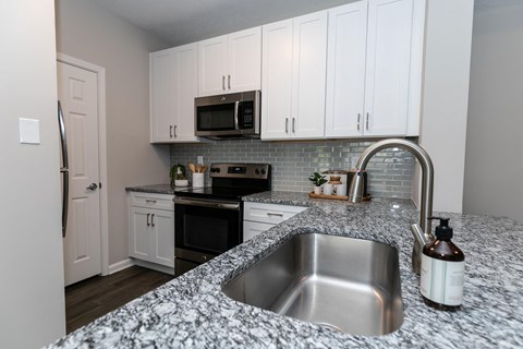 a kitchen with granite counter tops and white cabinets